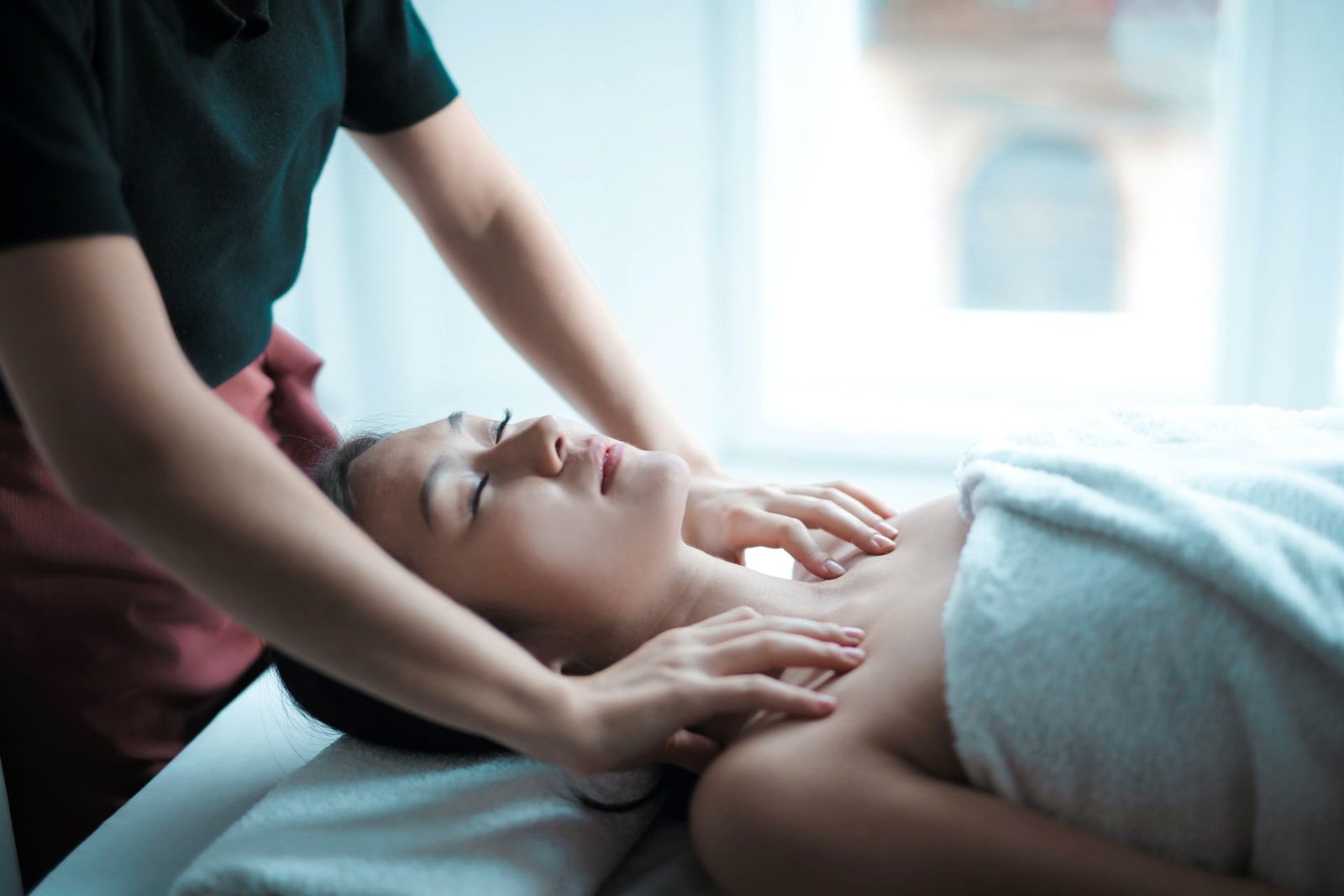 A professional massage therapist providing a relaxing massage to a woman lying on a spa bed, promoting wellness and relaxation.